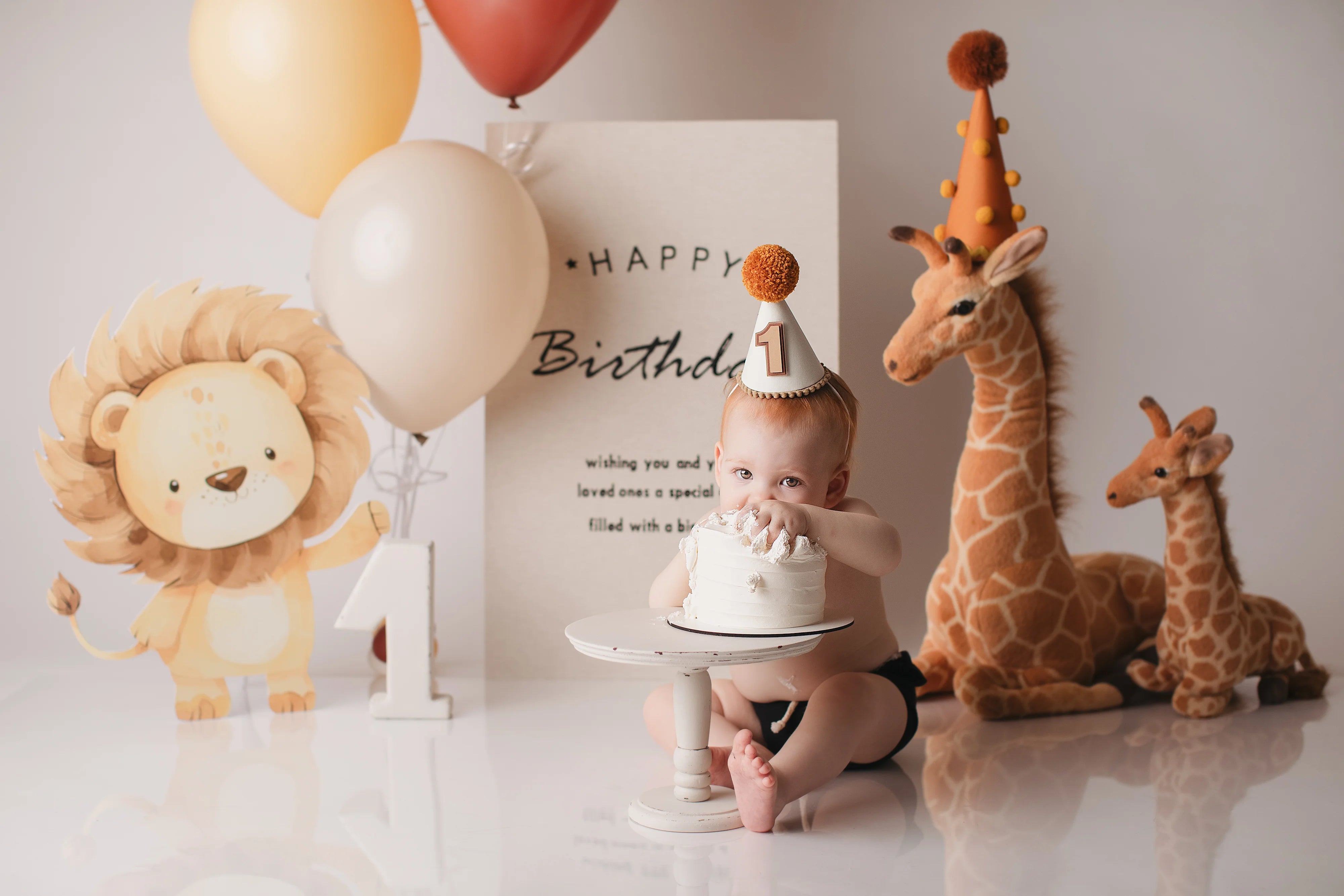 Child celebrating a first birthday with balloons, cake, and stuffed animals.