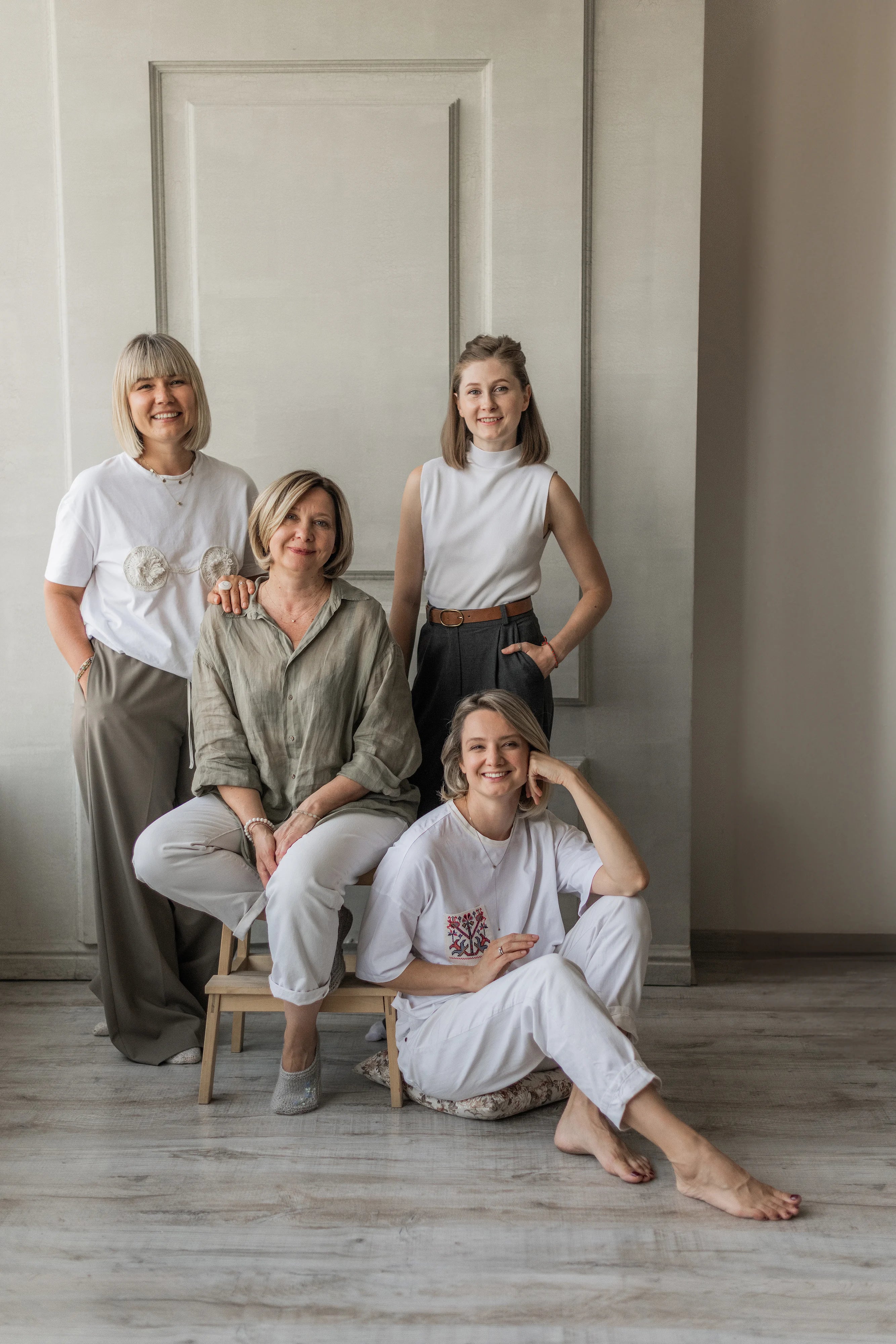 Four women posing together in a minimalistic indoor setting