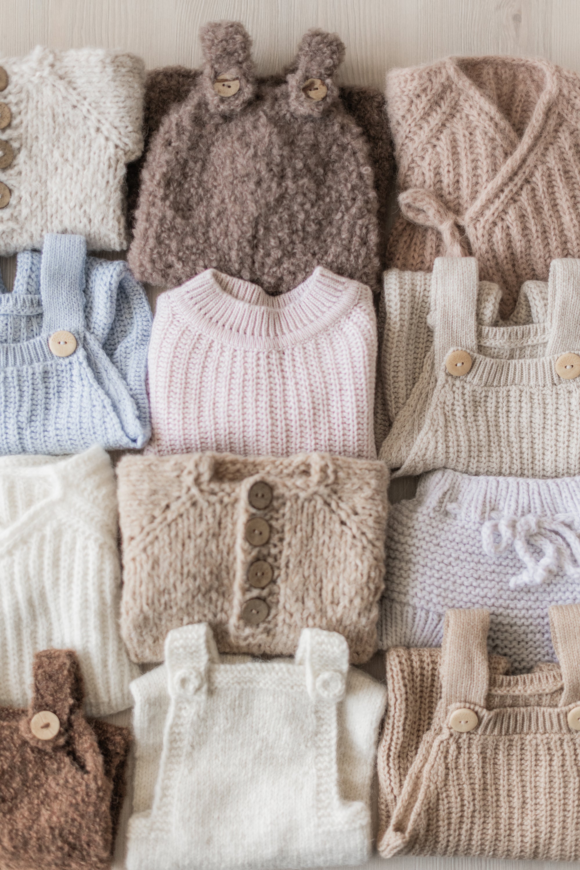 Collection of knitted baby outfits in various colors on a white background