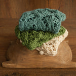 Soft hand-knitted newborn layer with tiny pom-poms — delicate wool prop ideal for baskets, wraps, or layered newborn photography setups.