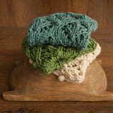Soft hand-knitted newborn layer with tiny pom-poms — delicate wool prop ideal for baskets, wraps, or layered newborn photography setups.
