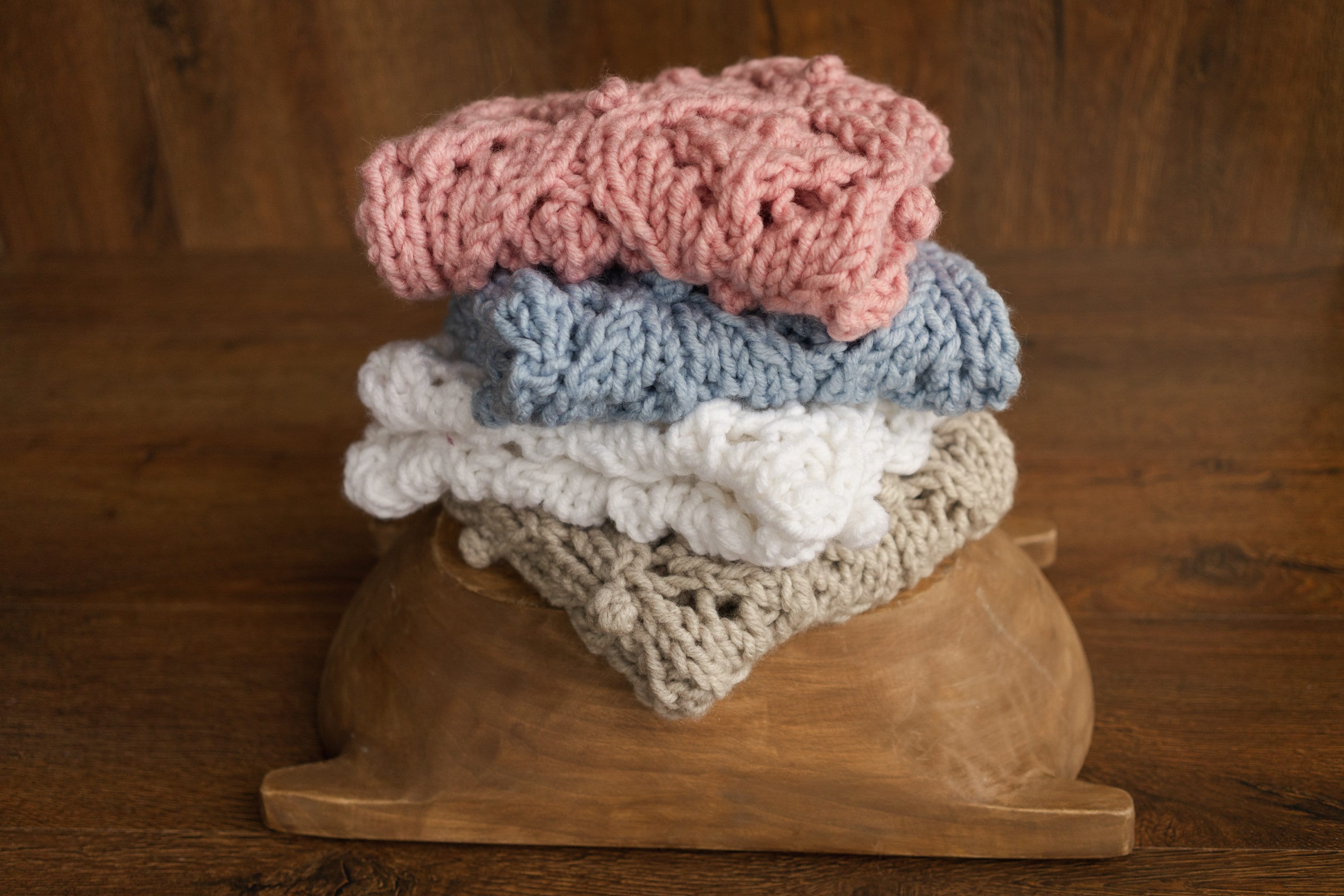 Soft hand-knitted newborn layer with tiny pom-poms — delicate wool prop ideal for baskets, wraps, or layered newborn photography setups.