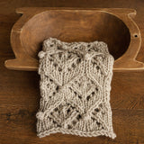 Soft hand-knitted newborn layer with tiny pom-poms — delicate wool prop ideal for baskets, wraps, or layered newborn photography setups.