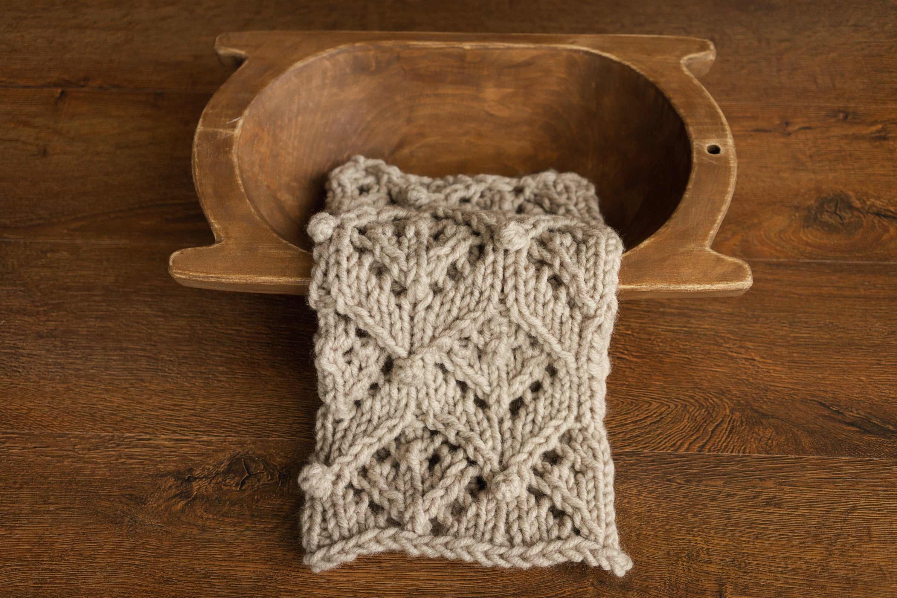 Soft hand-knitted newborn layer with tiny pom-poms — delicate wool prop ideal for baskets, wraps, or layered newborn photography setups.