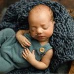 Soft hand-knitted newborn layer with tiny pom-poms — delicate wool prop ideal for baskets, wraps, or layered newborn photography setups.