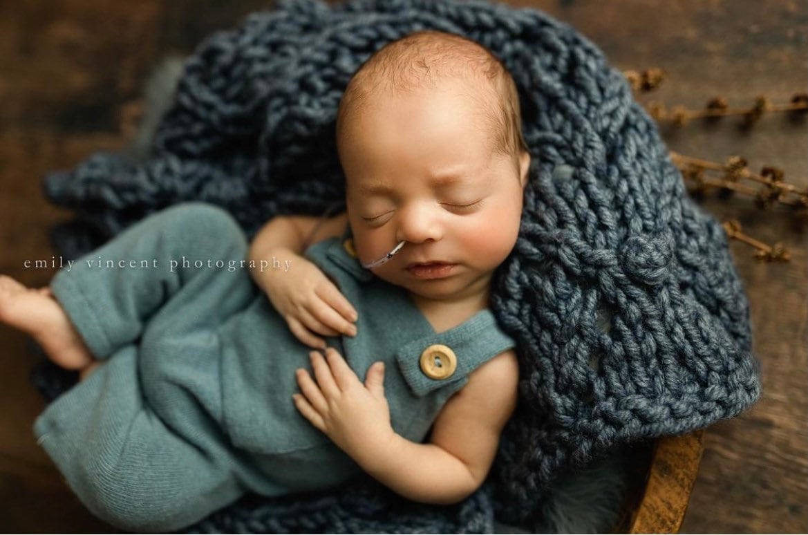 Soft hand-knitted newborn layer with tiny pom-poms — delicate wool prop ideal for baskets, wraps, or layered newborn photography setups.